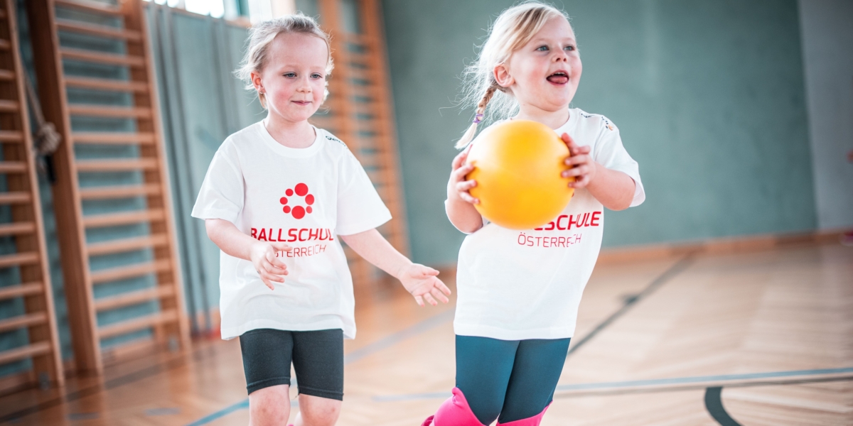 Zwei Kinder laufen mit Ball